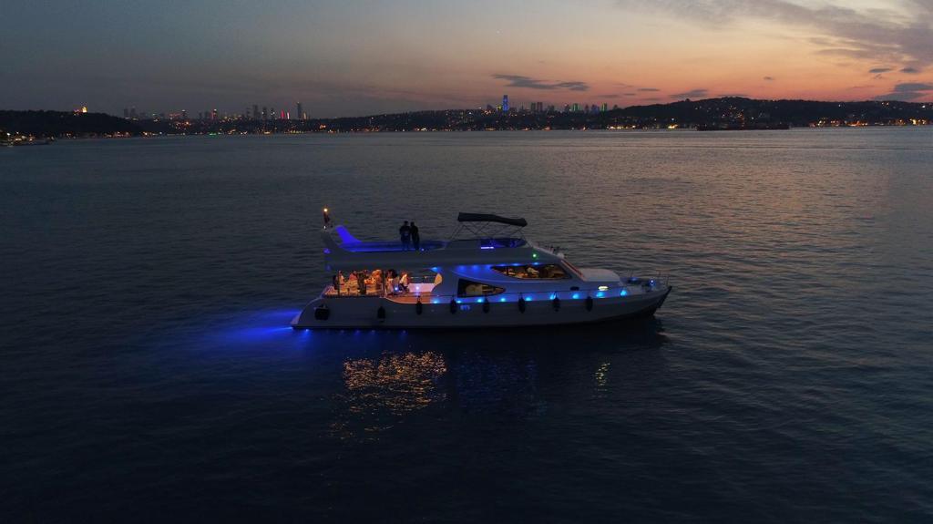 Intimate gathering of friends celebrating on a private yacht with Istanbul's skyline lighting up the evening.